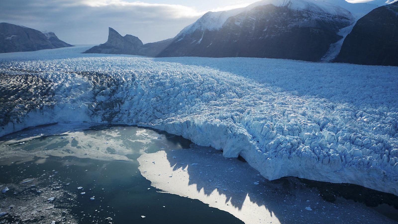 Lac recouvert partiellement d'un glacier sur fond de soleil couchant