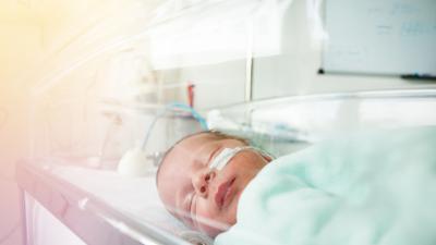 Bébé pérmaturé enveloppe dans une petite couverture verte dans un landau à l'hôpital 