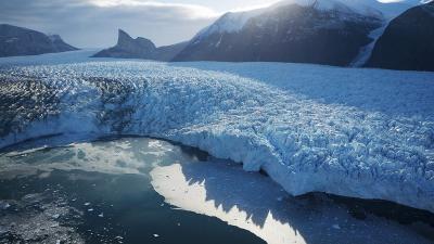 Lac recouvert partiellement d'un glacier sur fond de soleil couchant