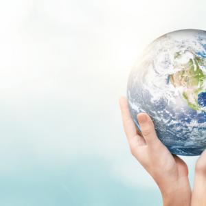La Terre soutenue par des mains sur un fond bleu très pâle 