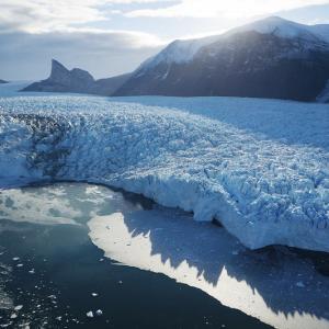 Lac recouvert partiellement d'un glacier sur fond de soleil couchant